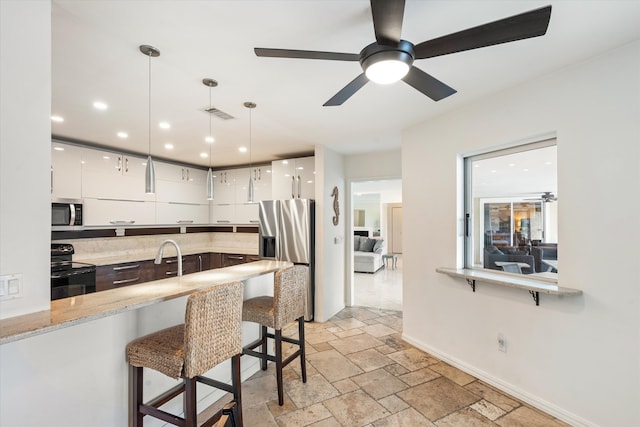 kitchen featuring stone tile flooring, appliances with stainless steel finishes, white cabinetry, modern cabinets, and a kitchen breakfast bar