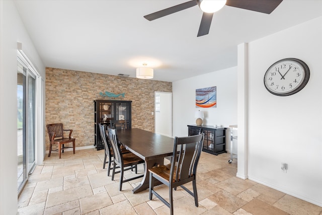 dining room featuring visible vents, a ceiling fan, stone tile flooring, and baseboards