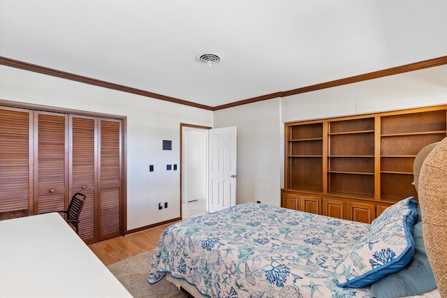 bedroom with light wood finished floors, a closet, visible vents, ornamental molding, and baseboards