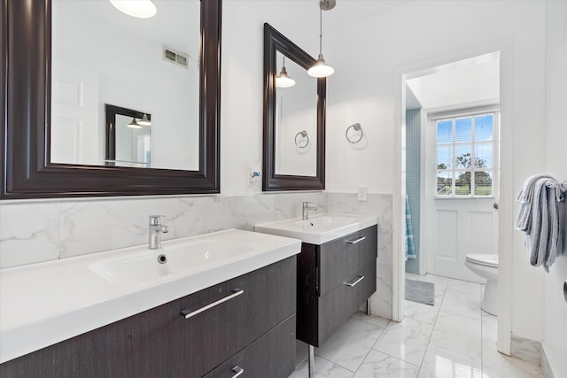 bathroom with visible vents, a wainscoted wall, a sink, marble finish floor, and tile walls