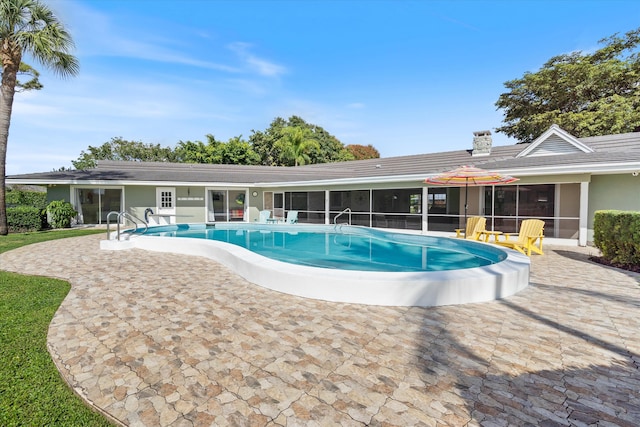 outdoor pool with a sunroom and a patio area