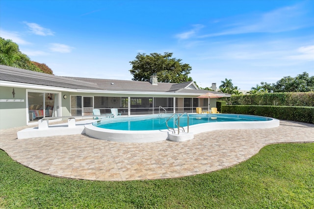 view of pool with a patio, a lawn, a sunroom, and a fenced in pool