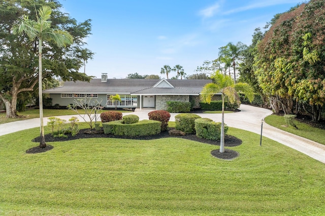 ranch-style home with concrete driveway and a front lawn