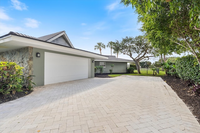 view of home's exterior with a garage, decorative driveway, and stucco siding