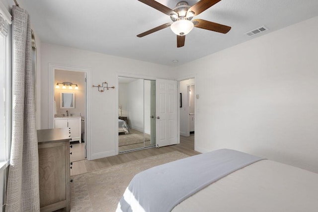 bedroom featuring sink, ensuite bath, ceiling fan, a closet, and light wood-type flooring