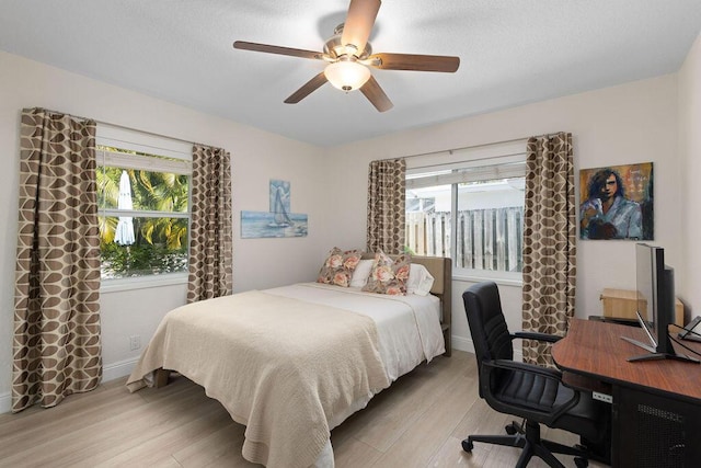 bedroom featuring multiple windows, ceiling fan, and light wood-type flooring