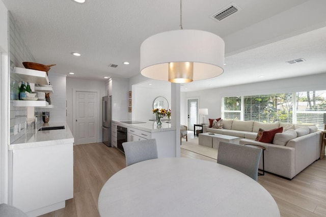 dining area with sink, light hardwood / wood-style flooring, and a textured ceiling