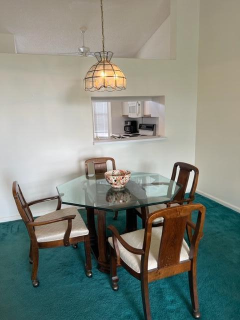 dining area featuring lofted ceiling and dark colored carpet