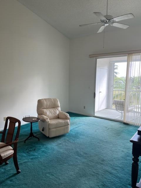 sitting room featuring ceiling fan, carpet floors, and a textured ceiling