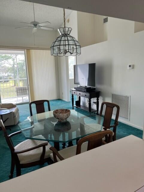 carpeted dining area featuring high vaulted ceiling