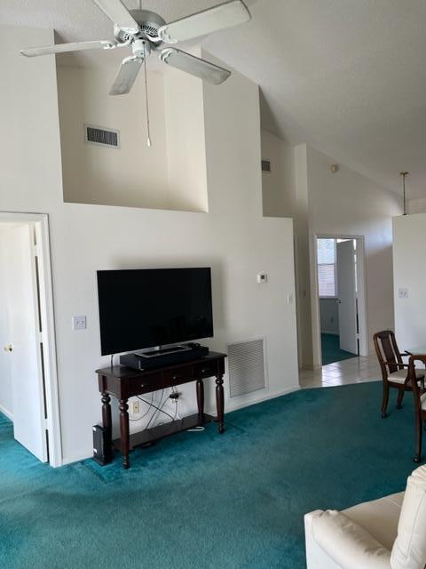 carpeted living room featuring high vaulted ceiling and ceiling fan