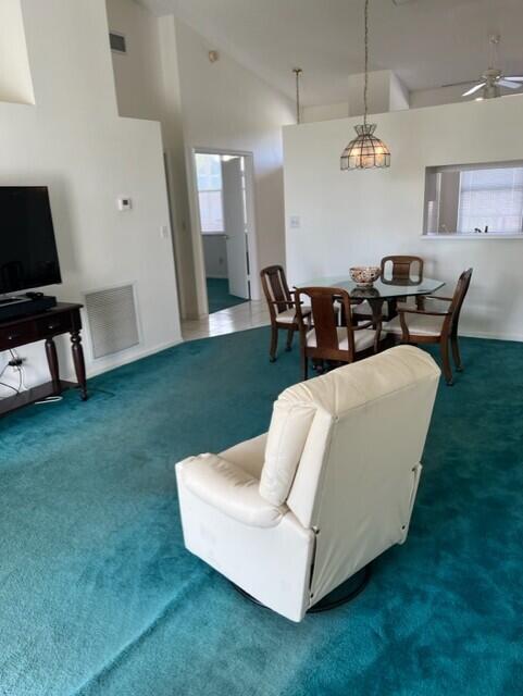 carpeted living room featuring ceiling fan and high vaulted ceiling