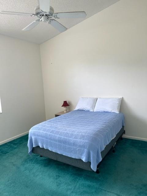 carpeted bedroom with ceiling fan and a textured ceiling