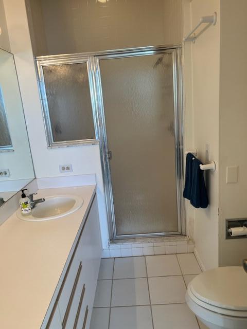 bathroom featuring toilet, a shower with door, tile patterned flooring, and vanity