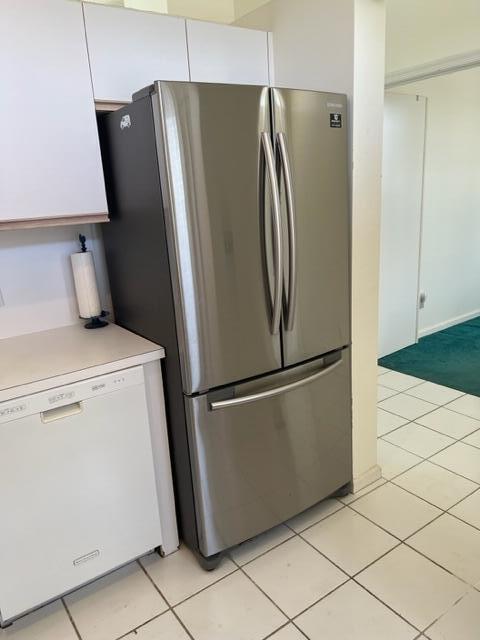 kitchen with white dishwasher, stainless steel fridge, white cabinets, and light tile patterned flooring