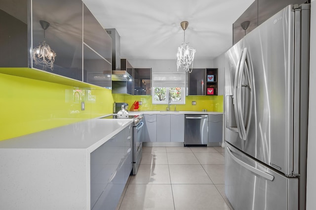 kitchen featuring decorative light fixtures, a chandelier, light tile patterned floors, stainless steel appliances, and wall chimney range hood