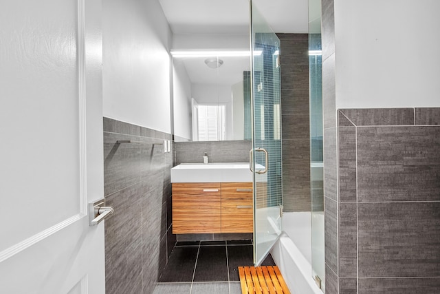 bathroom with tile patterned floors, vanity, a shower with door, and tile walls