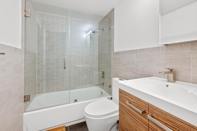 full bathroom featuring enclosed tub / shower combo, vanity, toilet, and tile walls