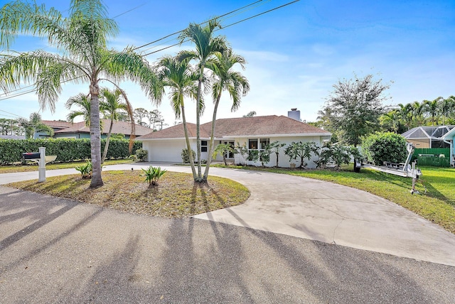 single story home featuring a chimney, curved driveway, stucco siding, an attached garage, and a front yard