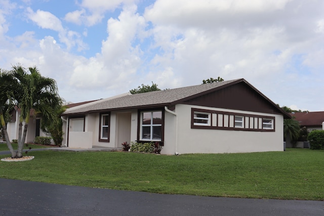 single story home featuring a front lawn, roof with shingles, and stucco siding