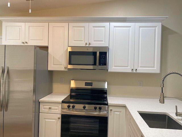 kitchen featuring appliances with stainless steel finishes, a sink, and white cabinetry