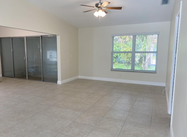 spare room featuring lofted ceiling, a ceiling fan, light tile patterned flooring, and baseboards