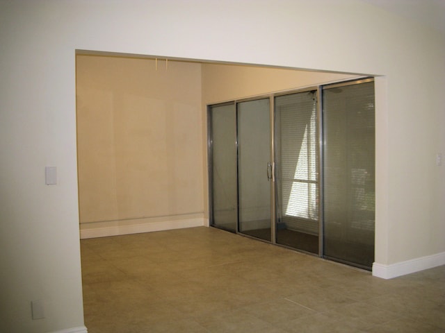 spare room with baseboards and tile patterned floors
