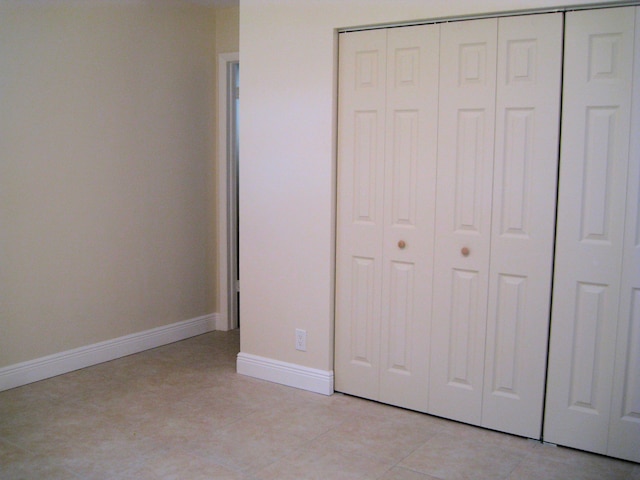 unfurnished bedroom featuring baseboards, a closet, and light tile patterned floors
