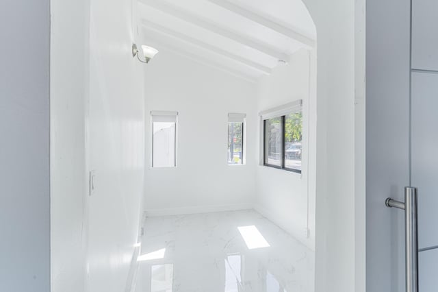 unfurnished room featuring vaulted ceiling with beams