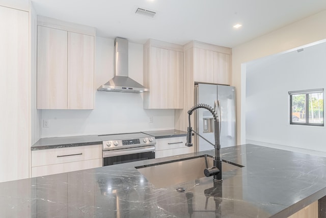 kitchen featuring wall chimney range hood, stainless steel appliances, sink, and light brown cabinets