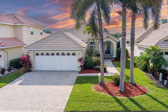 mediterranean / spanish-style home with a garage and a lawn