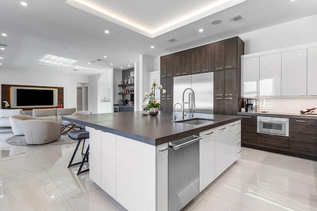 kitchen with visible vents, modern cabinets, a sink, dark countertops, and dark brown cabinetry