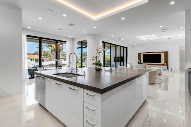 kitchen featuring dark countertops, a sink, a large island, white cabinetry, and modern cabinets