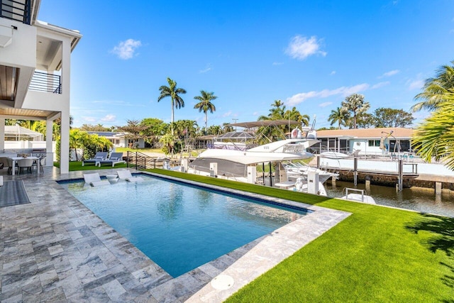 outdoor pool featuring a patio, fence, a dock, a water view, and a lawn