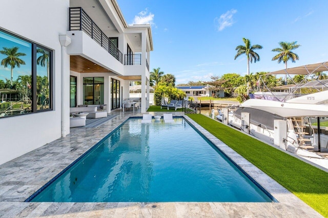 outdoor pool with a boat dock, a lawn, and a patio