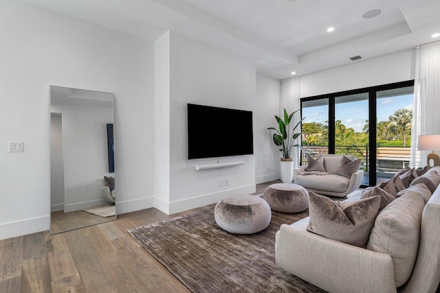 living area with visible vents, a tray ceiling, wood finished floors, recessed lighting, and baseboards