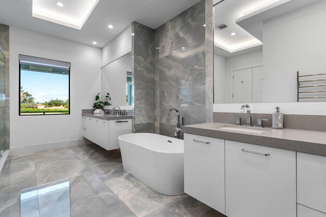 bathroom featuring a sink, marble finish floor, two vanities, and a freestanding bath