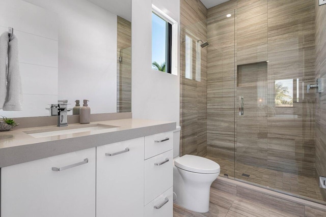 bathroom with vanity, a shower stall, and toilet