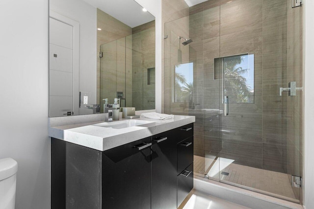 full bathroom with vanity, a shower stall, and toilet