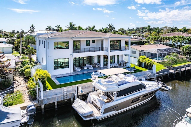 back of house with an outdoor pool, a water view, a balcony, and a patio