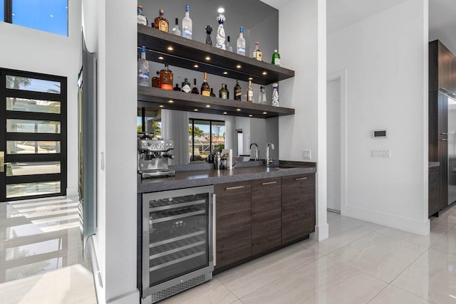 bar with a sink, wet bar, beverage cooler, and a towering ceiling