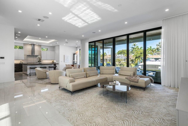 living area featuring a tray ceiling, recessed lighting, visible vents, and baseboards