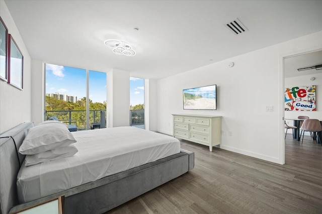 bedroom with wood-type flooring and a wall of windows