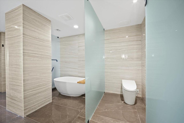 bathroom with a tub to relax in, tile walls, and toilet