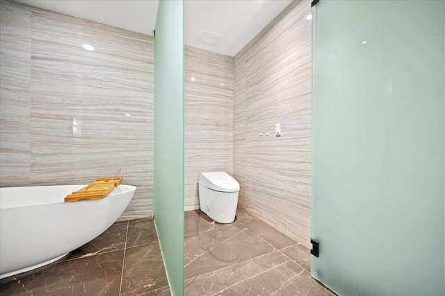 bathroom featuring tile walls, a bath, and toilet