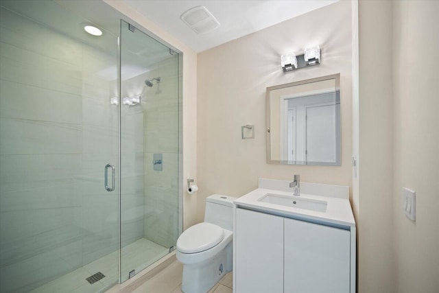 bathroom featuring tile patterned flooring, vanity, a shower with shower door, and toilet