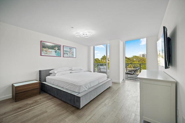 bedroom featuring light hardwood / wood-style flooring, access to outside, and floor to ceiling windows