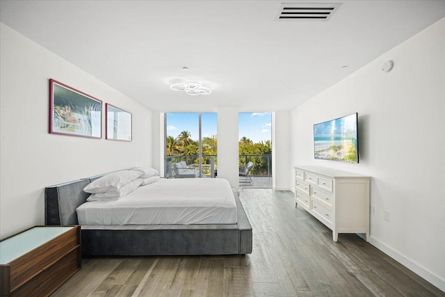 bedroom with expansive windows and dark hardwood / wood-style floors