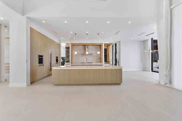 kitchen featuring a spacious island, wall chimney exhaust hood, modern cabinets, light brown cabinets, and recessed lighting