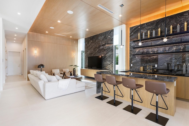 living room featuring wooden walls, recessed lighting, visible vents, and wet bar